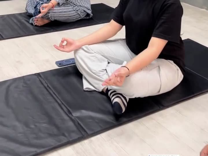 Members in a yoga class in the glass-walled group studio